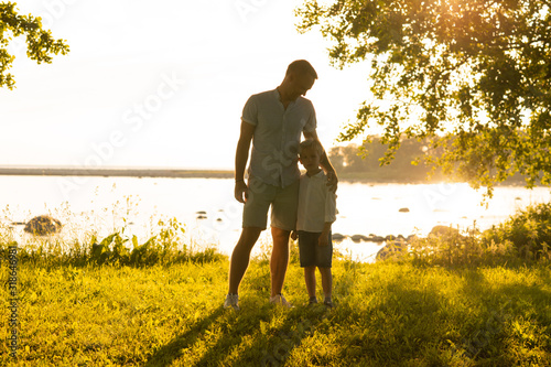 Father and his little son. Happy loving family walking outdoor in the light of sunset. © Acronym