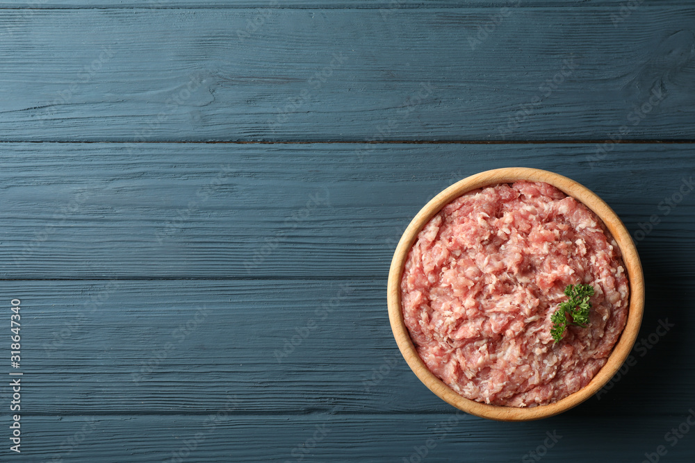 Bowl with minced meat on wooden background, top view