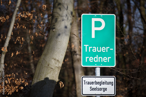  A parking lot sign at the forest in German with the words: bereavement speaker and a white sign with the words: bereavement counseling