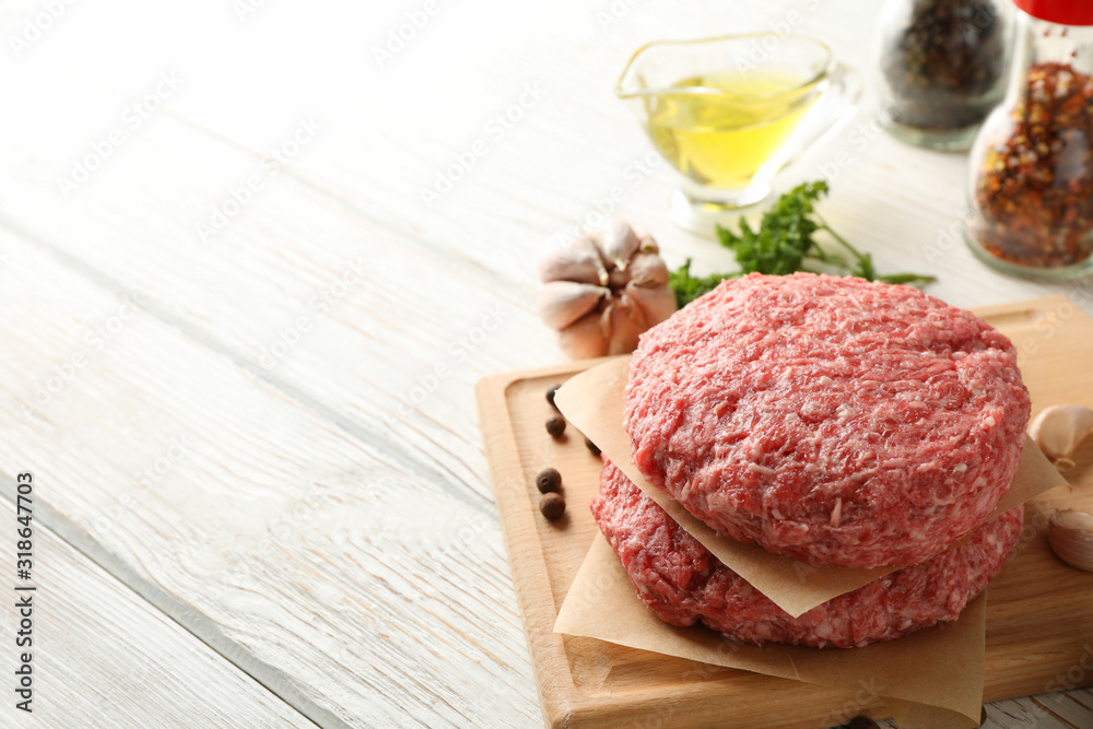 Spices and cutting board with minced meat on wooden background, close up