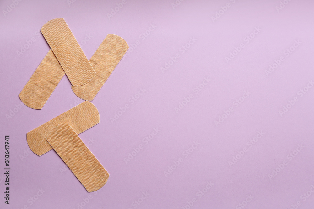 Sticking plasters on lilac background, flat lay. Space for text Sticking plasters on lilac background, flat lay. Space for text