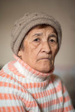 Portrait of an old woman in a studio in a knitted hat.