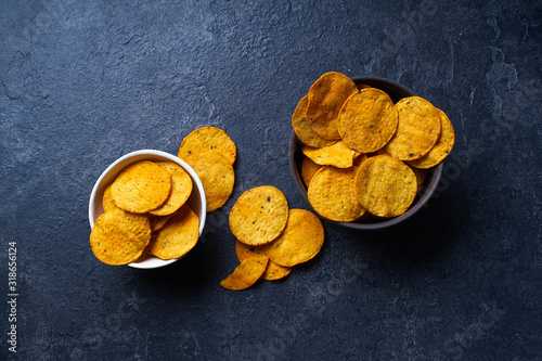  Mexican round-shaped nacho chips in two bowls. Top view chips on dark background with copy space