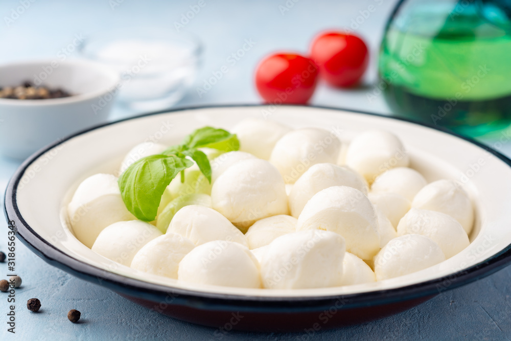 Mini mozzarella cheese in iron plate on blue concrete background. Selective focus.