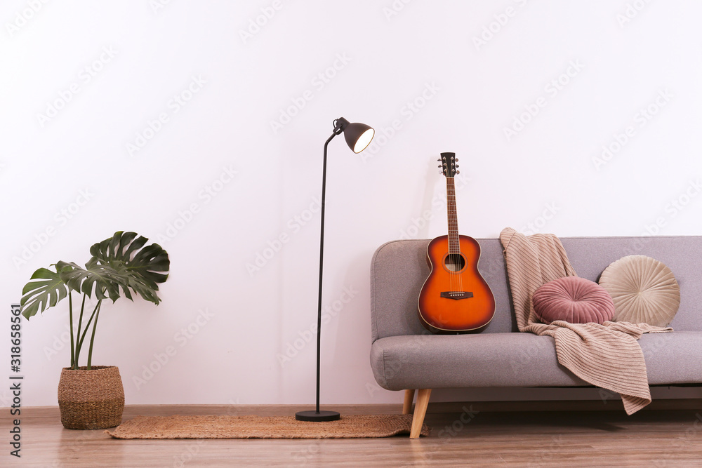 Minimalistic interior design concept. Acoustic guitar on grey textile sofa  in spacious room of loft style apartment with wood textured laminated  flooring. Background, copy space, close up. Stock Photo | Adobe Stock