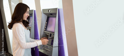 Obraz na płótnie Young Asian woman withdrawing money with a card at the automatic machine, Female