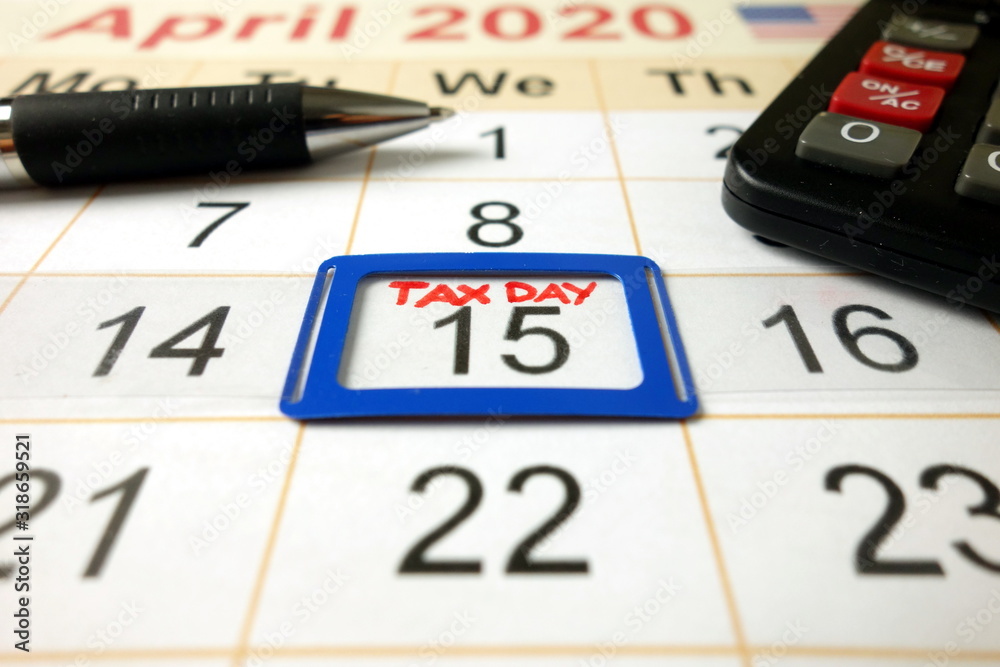 Monthly calendar showing date April 15th 2020 marked as tax day with pen and calculator Monthly calendar showing date April 15th 2020 marked as tax day with pen and calculator