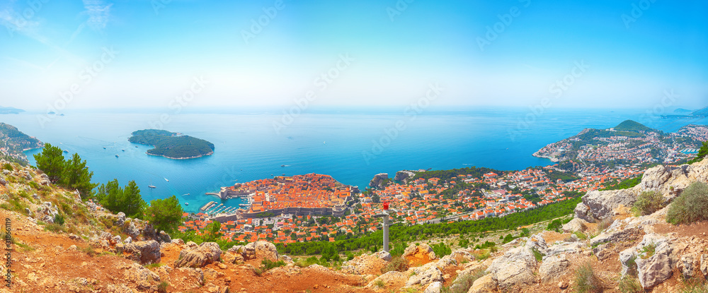 Aerial panoramic view of the old town of Dubrovnik with famous Cable Car on Srd mountain on a sunny day.