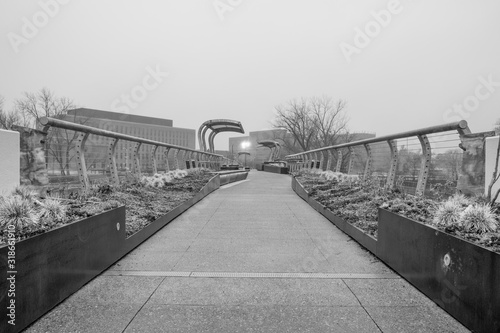 Outdoor footbridge with decorative shrub landscaping. Urban industrial walking foot bridge. 