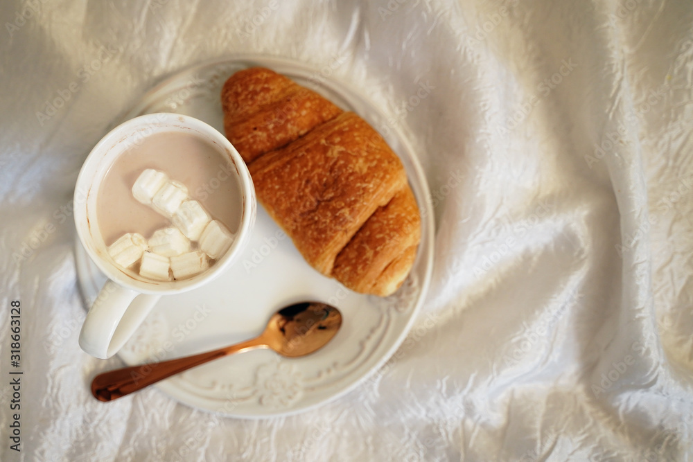 Fototapeta premium Breakfast in Flatley bed. Coffee mug and croissant are on the bed top view