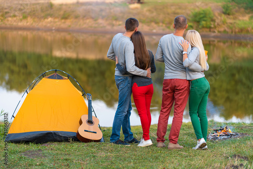 Picnic with friends in at lake near camping tent. Company friends having hike picnic nature background. Hikers relaxing during drink time. Summer picnic. Fun time with friends.