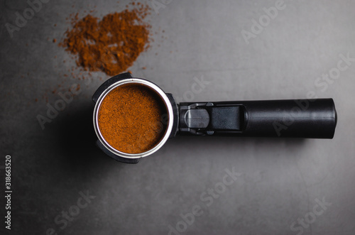 Top view of portafilter with ground coffee over black background photo