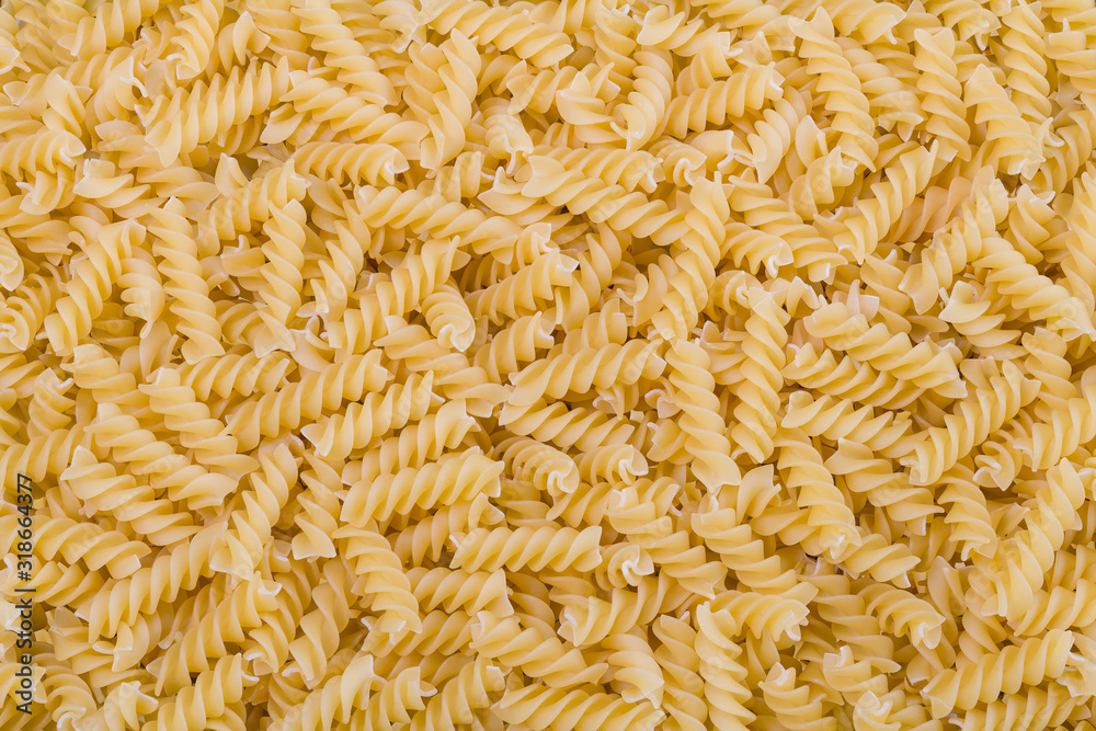 Raw dried extruded fusilli pasta texture. Staple food of Italian cuisine. Culinary background from short uncooked helical pastas for cooking side dishes. Use for recipe, packaging design, gastronomy. - obrazy, fototapety, plakaty 
