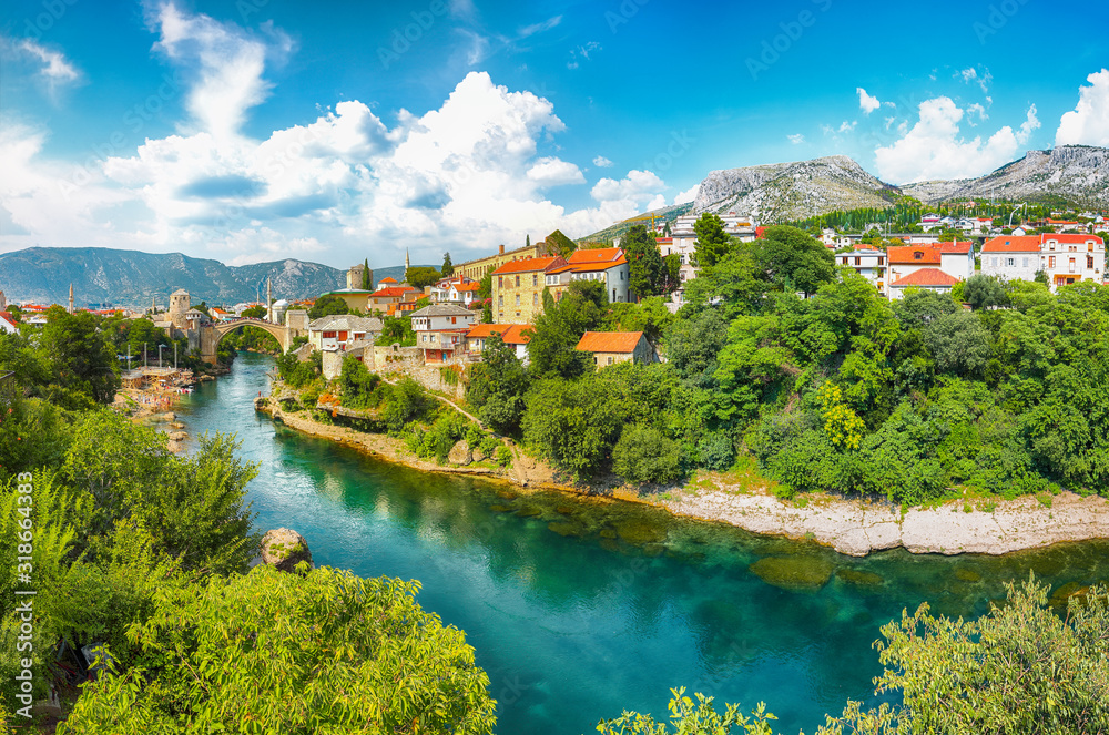 Fantastic Skyline of Mostar with the Mostar Bridge, houses and minarets, during sunny day.