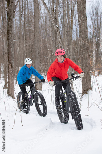 Obraz na płótnie Attractive couple riding fat bikes in the snow w salonie