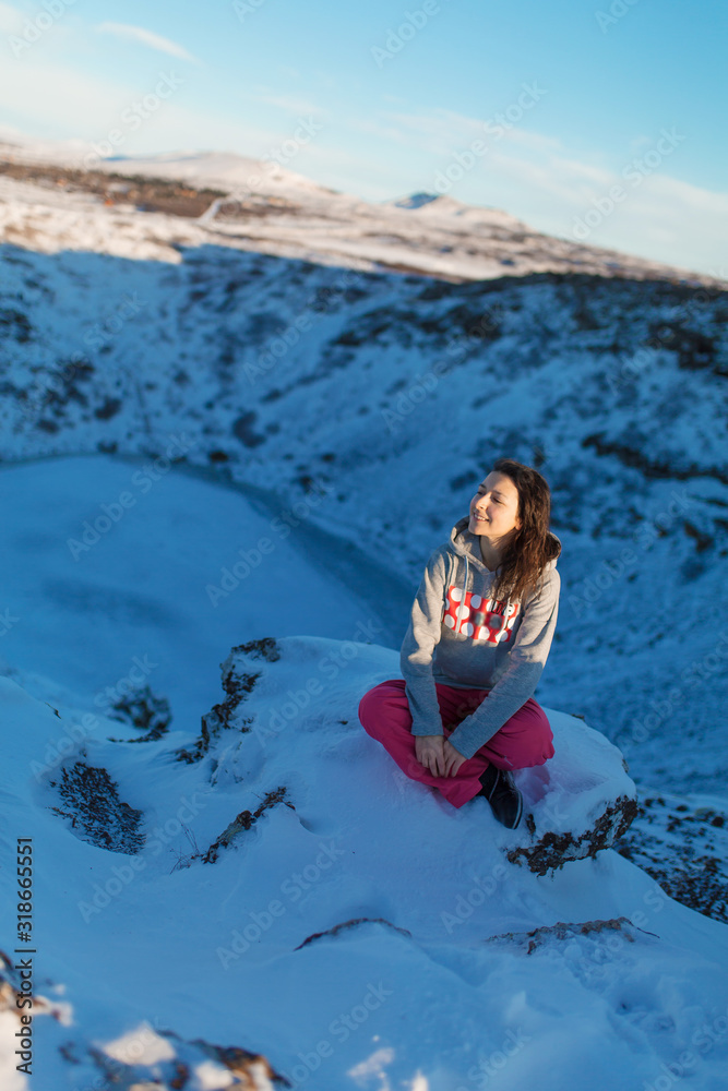 Beautiful girl on the background of lake Kerid frozen in winter in the crater of an extinct volcano. Incredible iceland landscape in winter