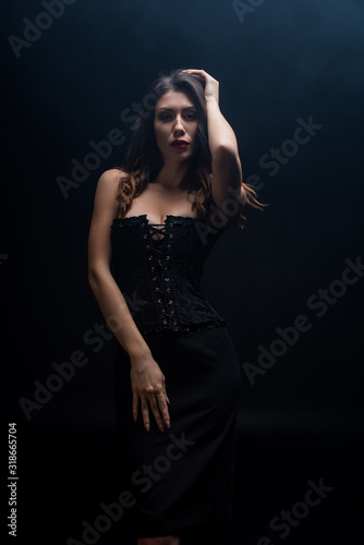 Sensual woman in corset looking at camera isolated on black