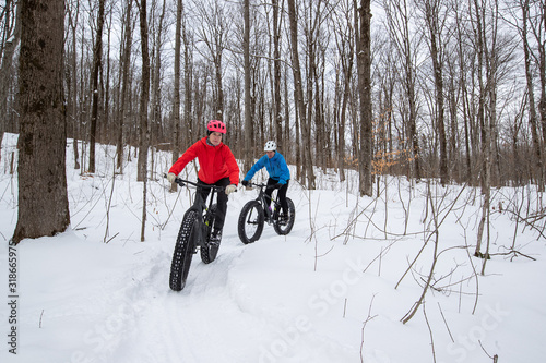 Obraz na płótnie Attractive couple riding fat bikes in the snow w salonie