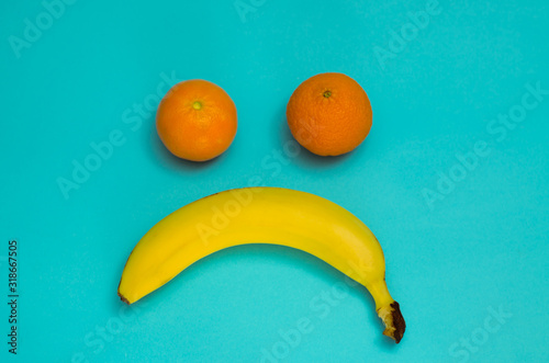 Sad  muzzle of fruits. Banana and two tangerines