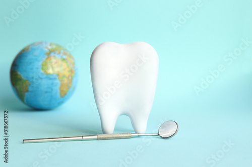 White tooth with dental instruments on a blue background in honor of the international day of the dentist on February 9 © Natalya