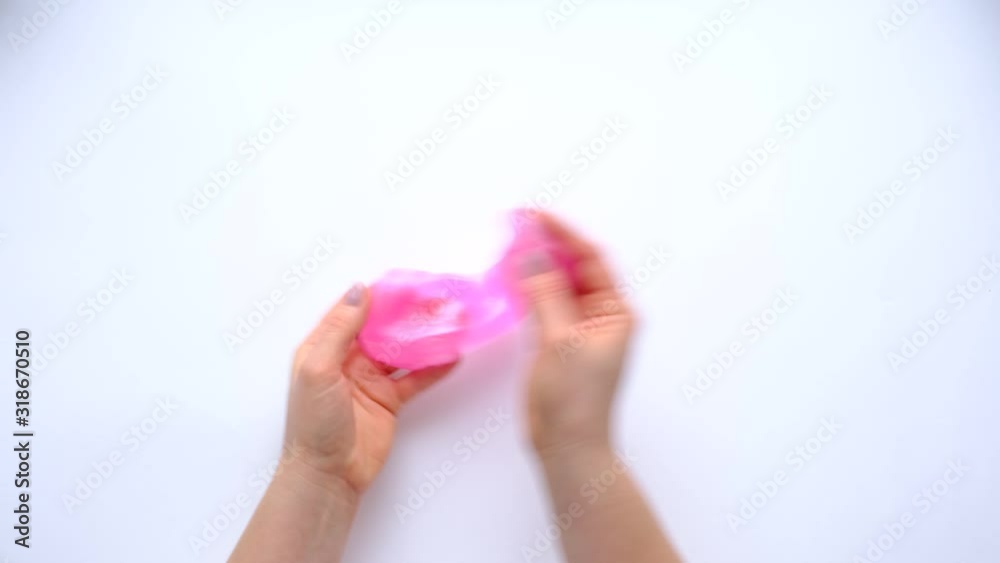 Woman hands playing with pink slime on white background. Trendy liquid toy. Top view. 4k footage. Woman hands playing with pink slime on white background. Trendy liquid toy. Top view. 4k footage.