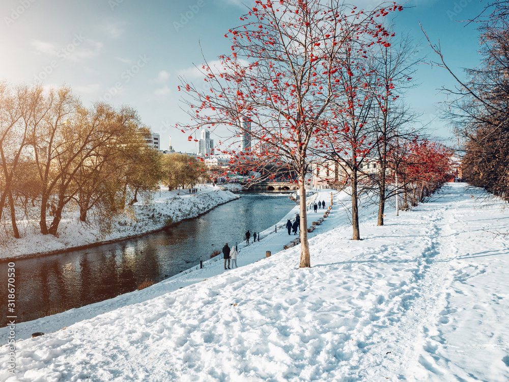 Naklejka premium Park in Yekaterinburg city along the Iset river at winter time at sunny day with people walking