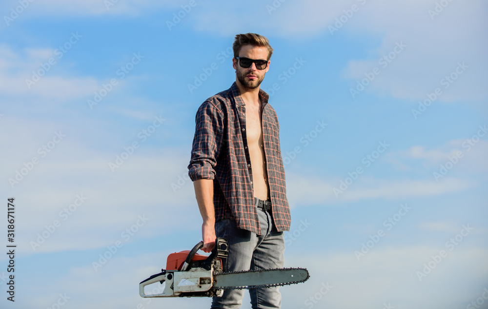 Lumberjack with chainsaw in his hands. Dangerous job. Feeling confident. Risky temper. Powerful chainsaw. Sharp blade. Handsome man with chainsaw blue sky background. Gardener lumberjack equipment Lumberjack with chainsaw in his hands. Dangerous job. Feeling confident. Risky temper. Powerful chainsaw. Sharp blade. Handsome man with chainsaw blue sky background. Gardener lumberjack equipment
