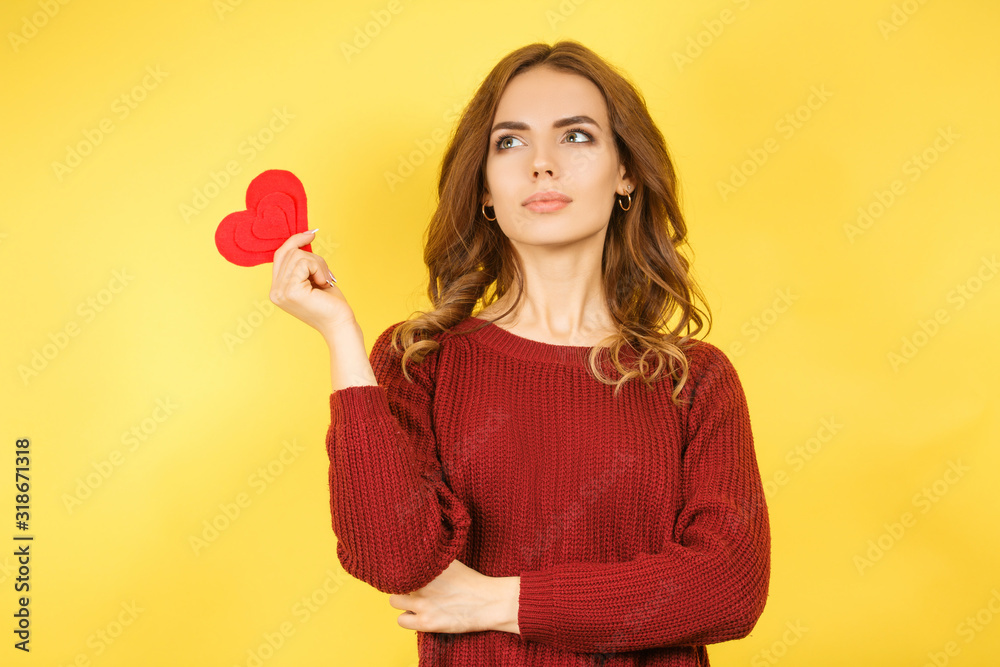 woman holding red heart on yellow background woman holding red heart on yellow background