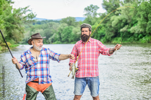 two happy fisherman with fishing rod and net. hunting tourism. father and son fishing. Camping on the shore of lake. Big game fishing. friendship. concept of a rural getaway. hobby. Fly Fishing Time