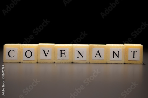 The word COVENANT written on wooden cubes isolated on a black background... photo