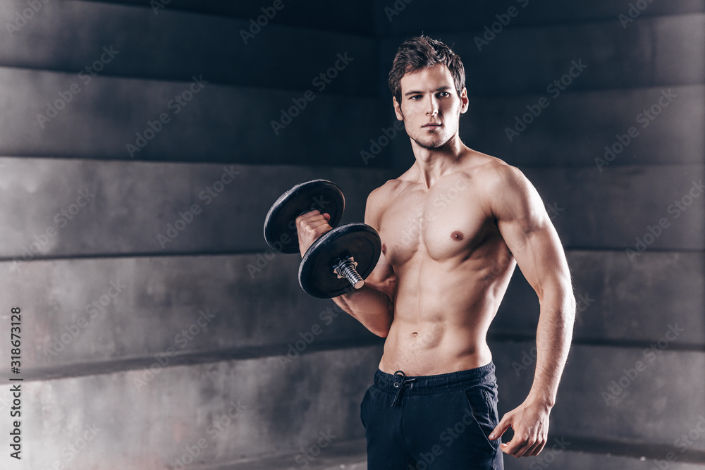 Strong handsome man with dumbbells.