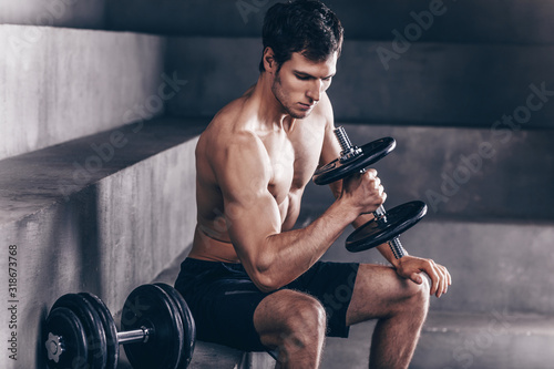 Strong man with heavy dumbbells on workout.