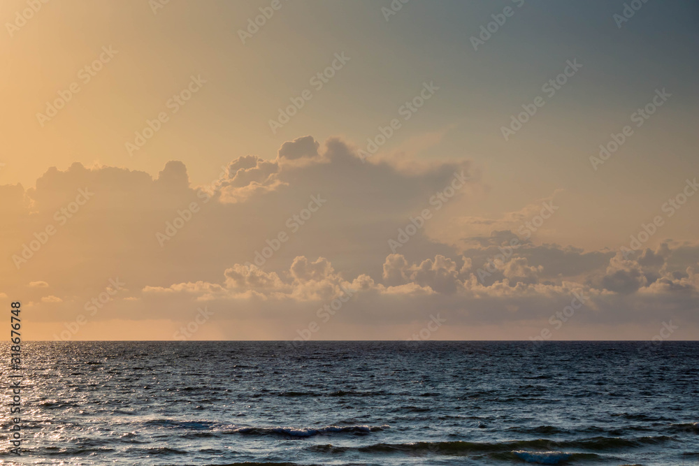 Glow and dark blue surface of sea at sunset and sky with cumulus cloud