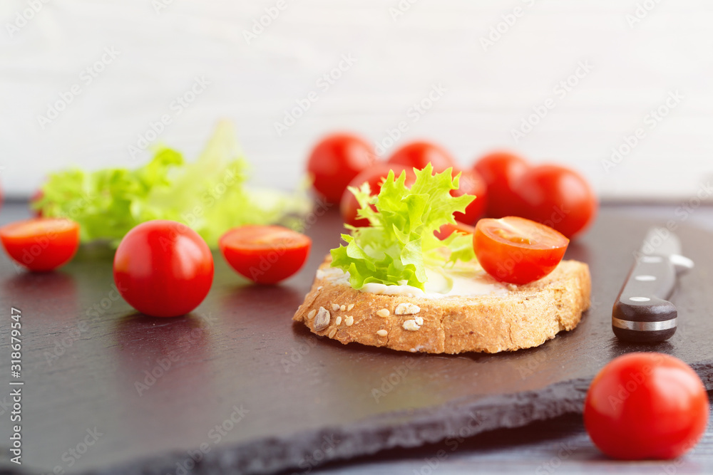 Sandwiches with soft cheese, lettuce and tomatoes on grain bread.