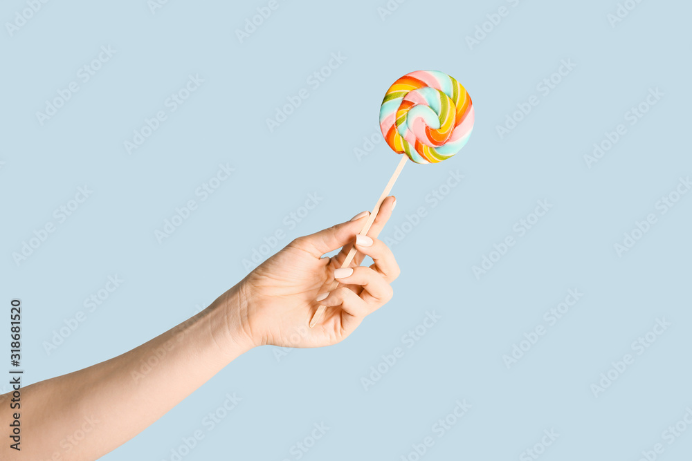 Female hand with sweet lollipop on color background Female hand with sweet lollipop on color background