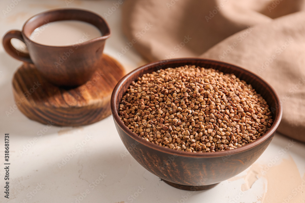 Bowl with raw buckwheat and jug of milk on table Bowl with raw buckwheat and jug of milk on table