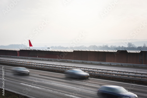 Highway and airport side by side. Airplane on runway and cars