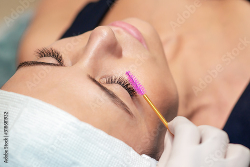 Young woman receiving eyelash extension procedure in a beauty salon, close up.