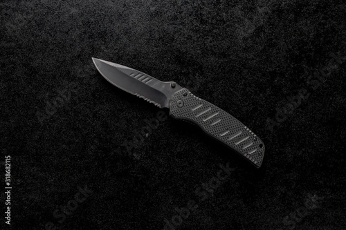 Closeup shot of an EDC pocket knife with a black handle on a black background
