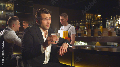 Man drinks alcohol at the barand looks at the camera with smile photo