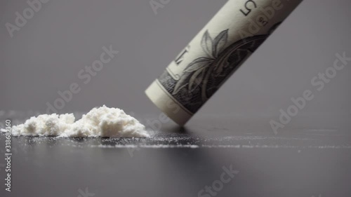 Drug Abuse. A rolled banknote snorting a line of cocaine powder. Problems with drugs concept. Grey background. Close-up macro shot.