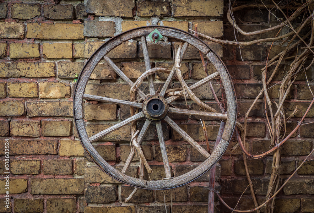The old wooden cart wheel against brick wall
