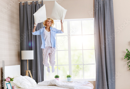 happy young woman laughing and jumping on the bed in   morning at home.