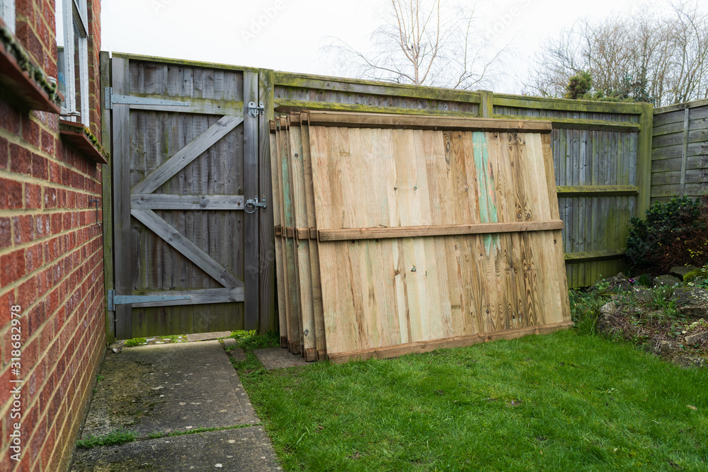 Replacement fence panels with vertical slats stacked waiting for installation in a residential back garden or yard.. Replacement fence panels with vertical slats stacked waiting for installation in a residential back garden or yard..