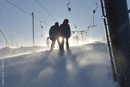 Фотография Silhouettes of persons in ski lift a windy afternoon, Sweden, Sälen, 2019