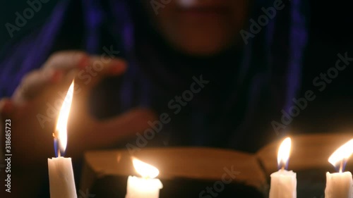 Witch telling spell from old book under candles. Fortune teller call spirits. Halloween concept. Mystical video 4k. Occult and esoteric atmosphere  photo