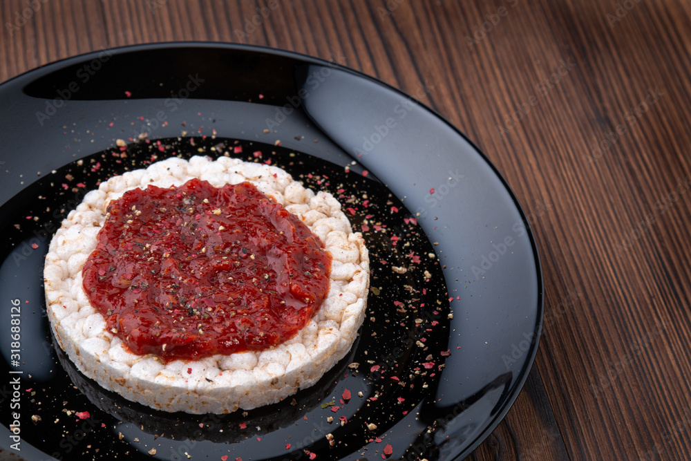 Rice cakes with spicy red sauce on a black plate on a wooden table Rice cakes with spicy red sauce on a black plate on a wooden table