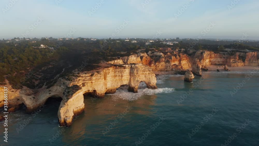 Aerial view of cliff with arch rock at Praia da Marinha at sunrise Aerial view of cliff with arch rock at Praia da Marinha at sunrise