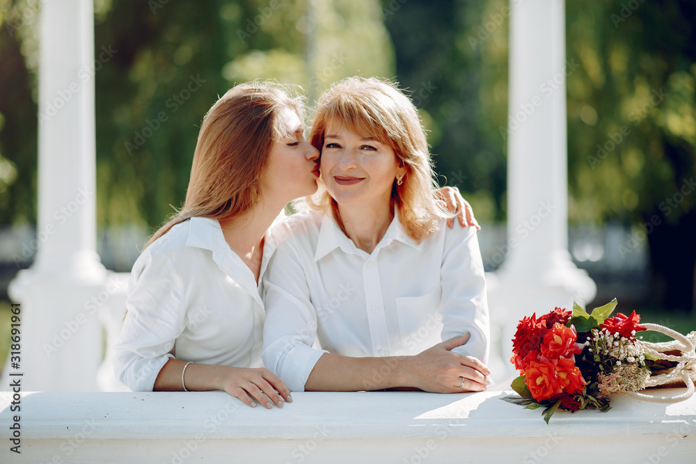 Naklejka premium Elegant mother with young daughter. Family in a park. Women with a bouquet of flowers