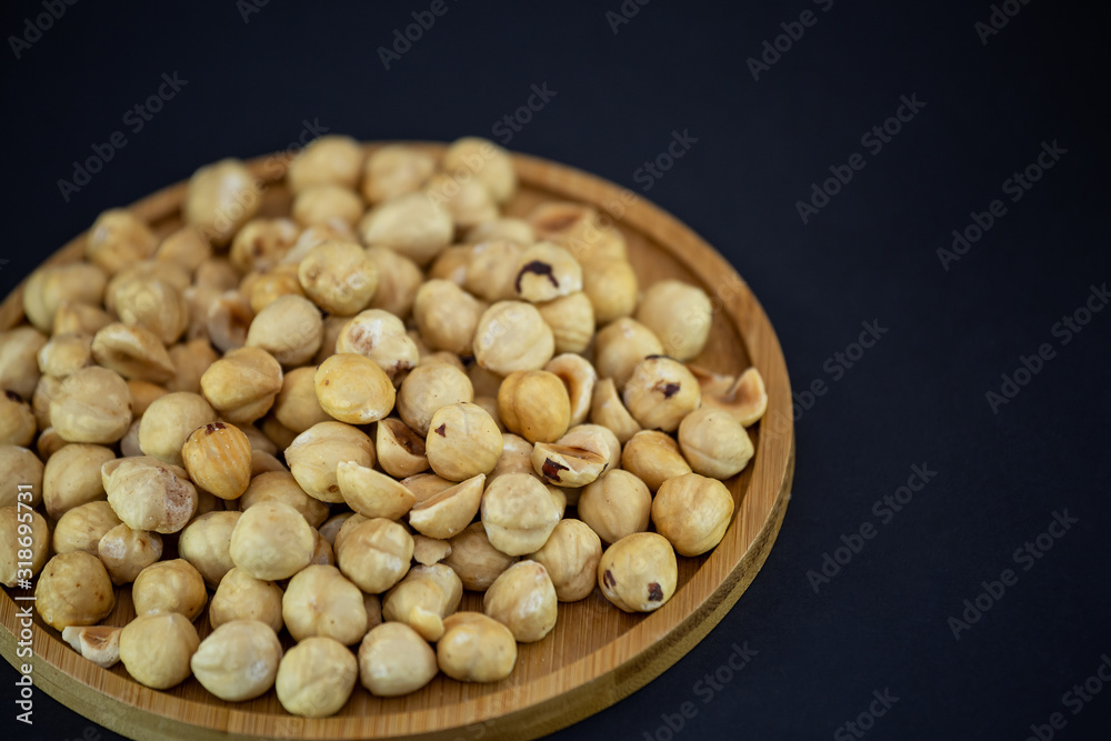Hazelnut nut or noisettes nuts group Protein and healthy food for diet in a wooden plate on a black background. Hazelnut nut or noisettes nuts group Protein and healthy food for diet in a wooden plate on a black background.